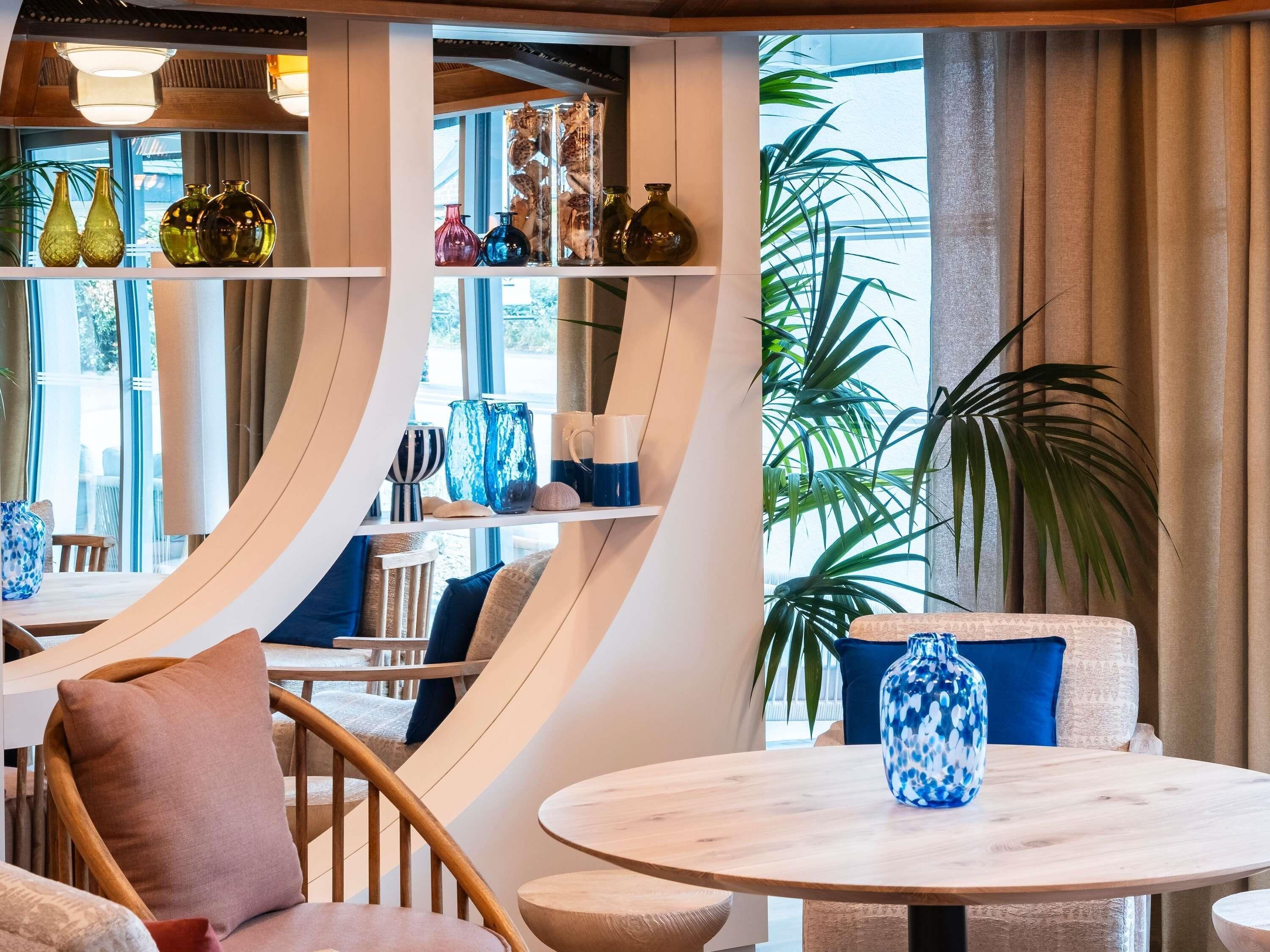 Un intérieur moderne avec des tables rondes, des chaises et divers objets décoratifs disposés sur des étagères.