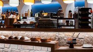 A bar area with a stone wall, wooden counter, and hanging pendant lights. - Mercure Quiberon Hotel & Spa (Quiberon)
