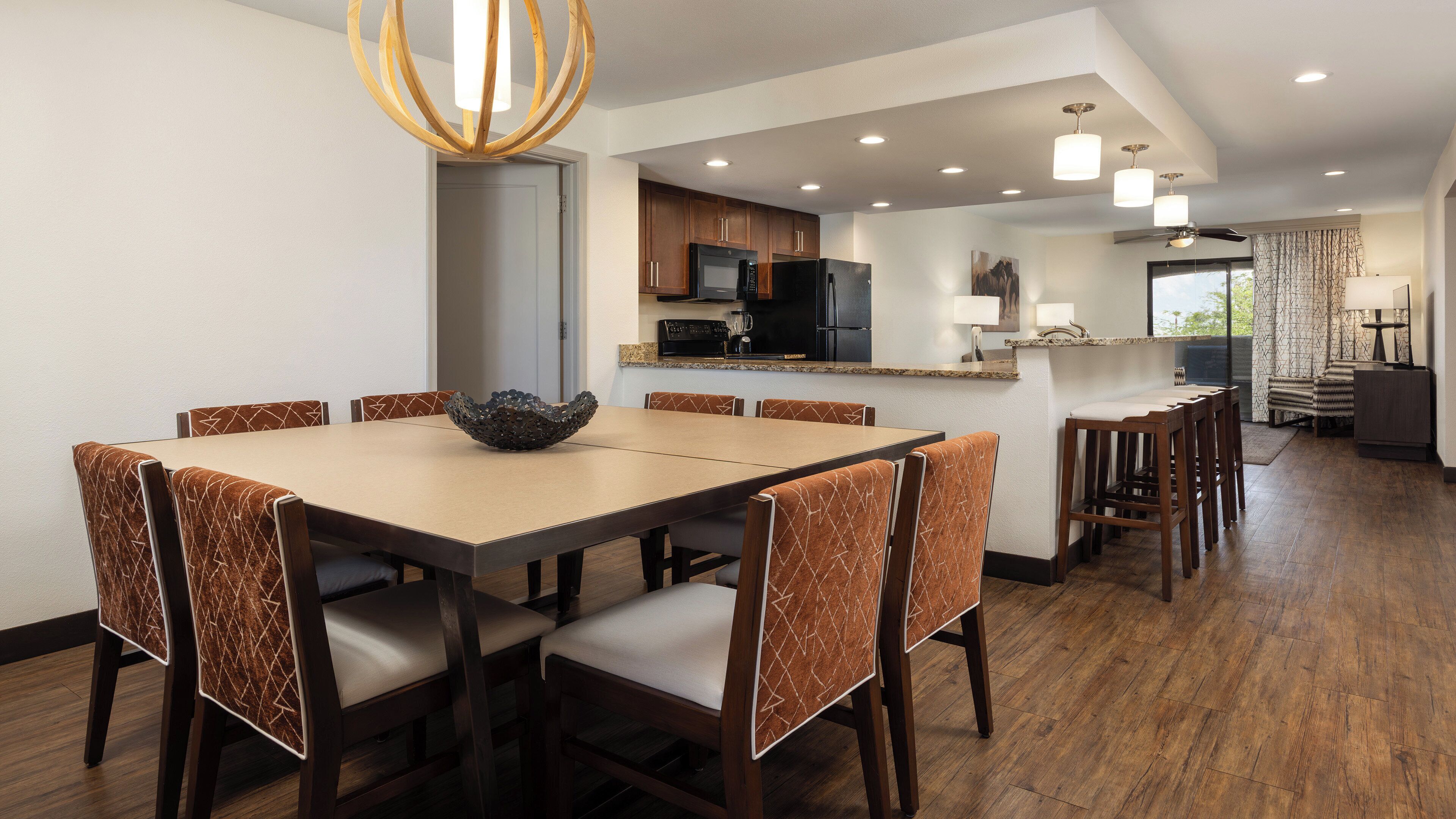 A modern dining area with a large table, six chairs, and a decorative bowl centerpiece.