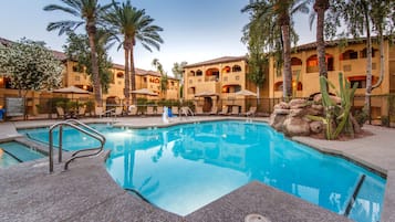 Relax by the pool surrounded by palm trees and cacti.