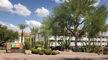 Un hôtel doté d’un jardin désertique, de cactus et d’un panneau indiquant les offres de vacances du Holiday Inn Club.