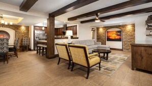 A spacious living area with a stone accent wall, a large sofa, and a dining area with a kitchen in the background. - Holiday Inn Club Vacations Scottsdale Resort by IHG (Scottsdale)