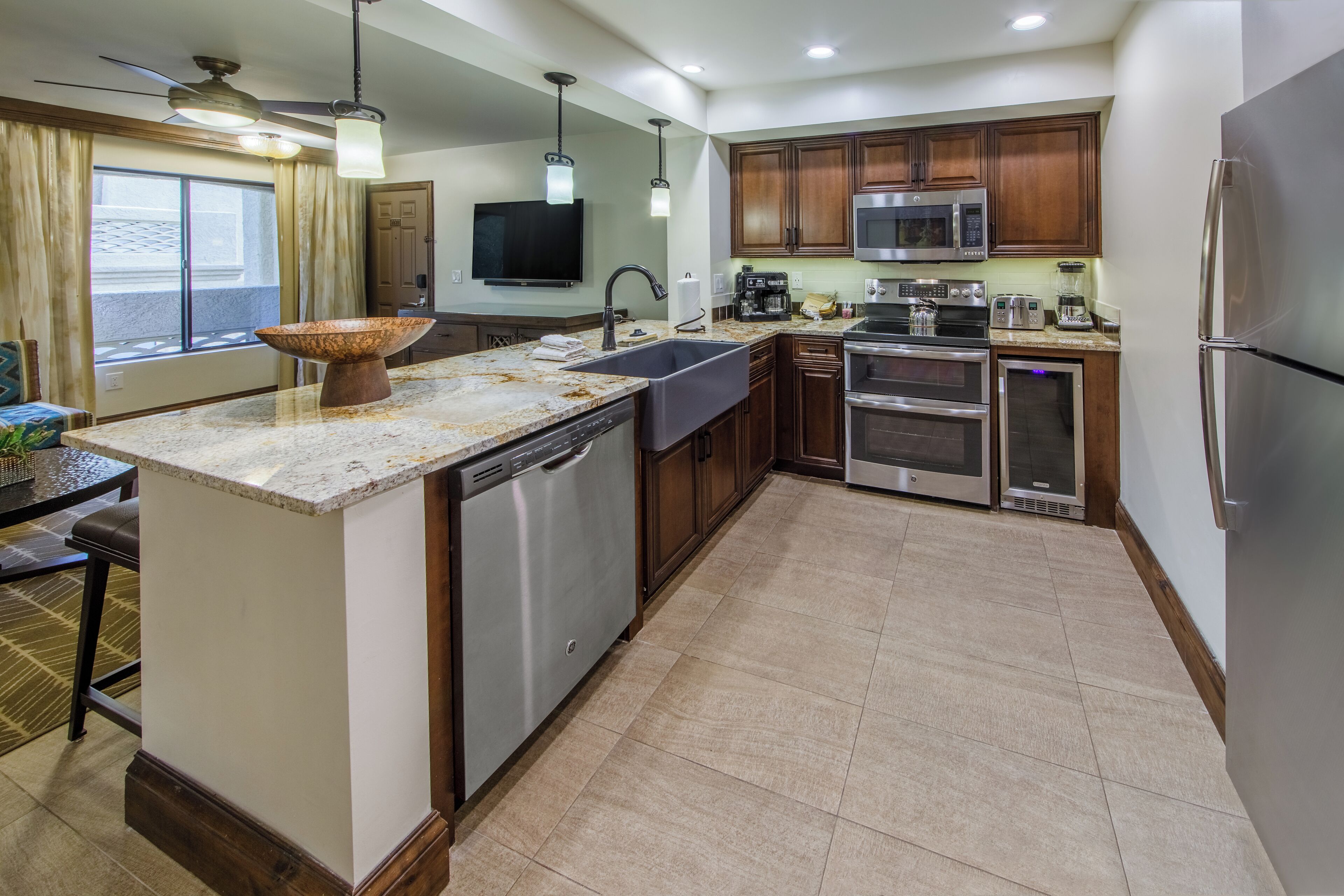 A modern kitchen with a granite countertop, stainless steel appliances, and wooden cabinets.