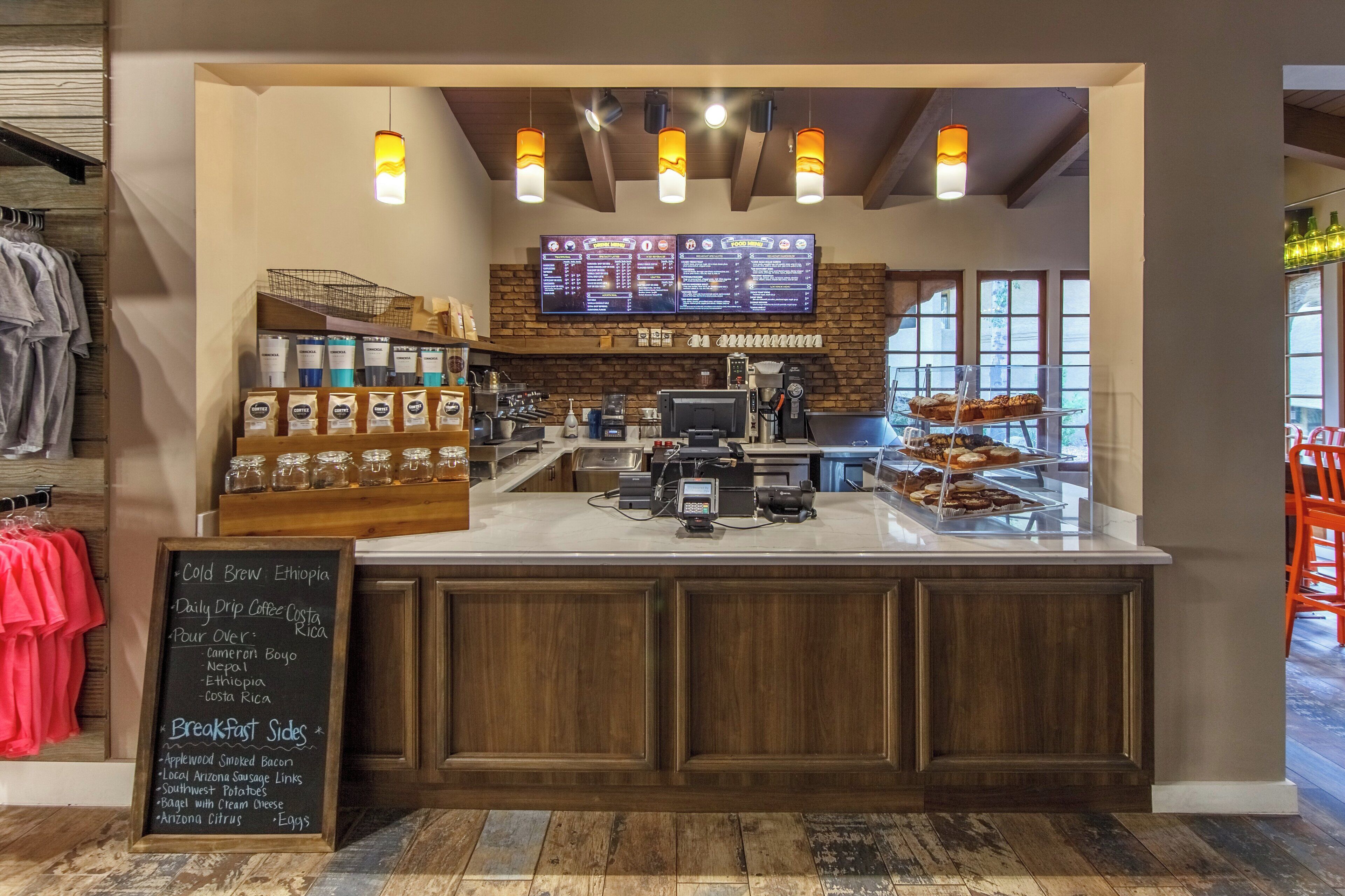 A coffee shop interior with a menu board, coffee beans display, and a counter with pastries.