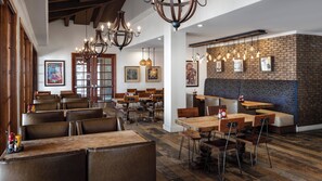 A restaurant interior with wooden tables and chairs, hanging lights, and a brick wall. - Holiday Inn Club Vacations Scottsdale Resort by IHG (Scottsdale)