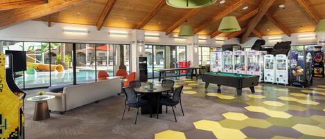 A spacious indoor area with a pool, seating, and arcade games.
