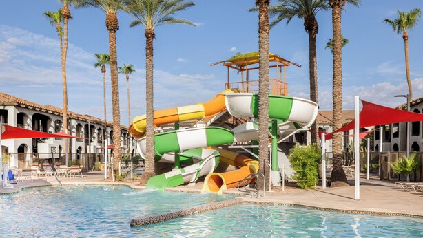 A water park with a multi-level water slide, palm trees, and a pool area with lounge chairs. - Holiday Inn Club Vacations Scottsdale Resort by IHG (Scottsdale)