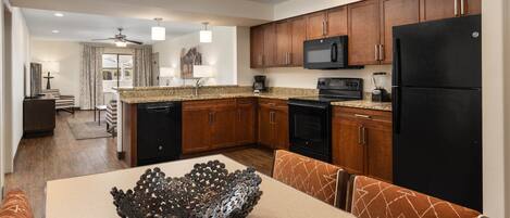 A modern kitchen with wooden cabinets, a black refrigerator, a microwave, and a dishwasher.