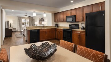 Una cocina moderna con armarios de madera, un refrigerador negro, un microondas y un lavavajillas.