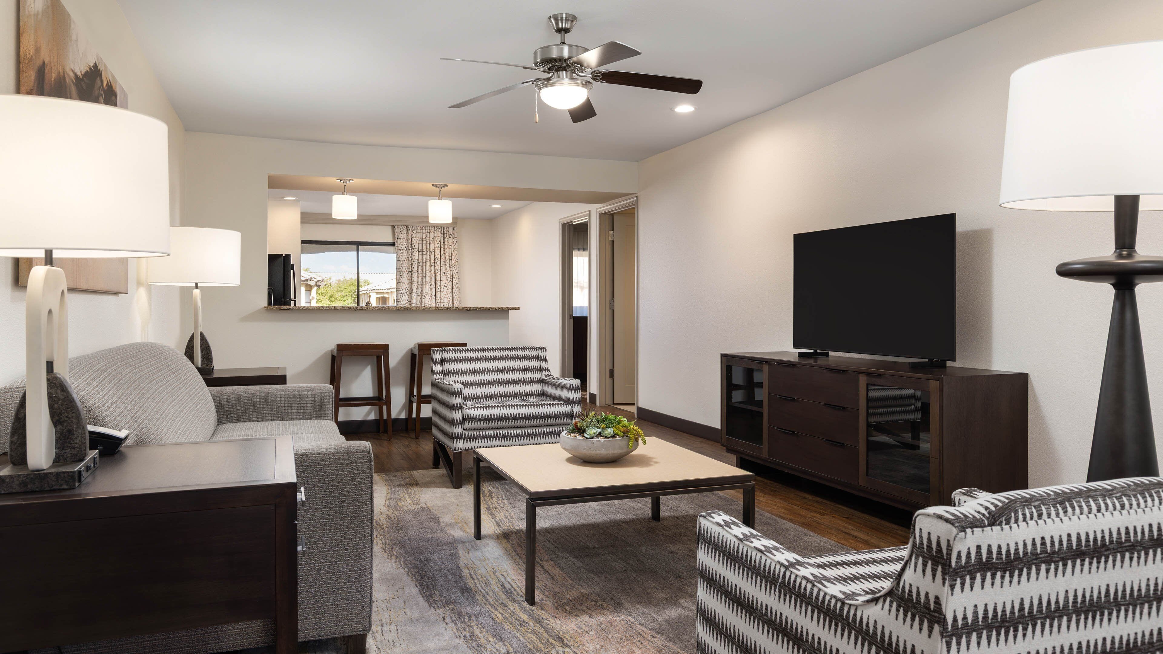 A modern living room with a sofa, armchairs, a coffee table, and a TV.