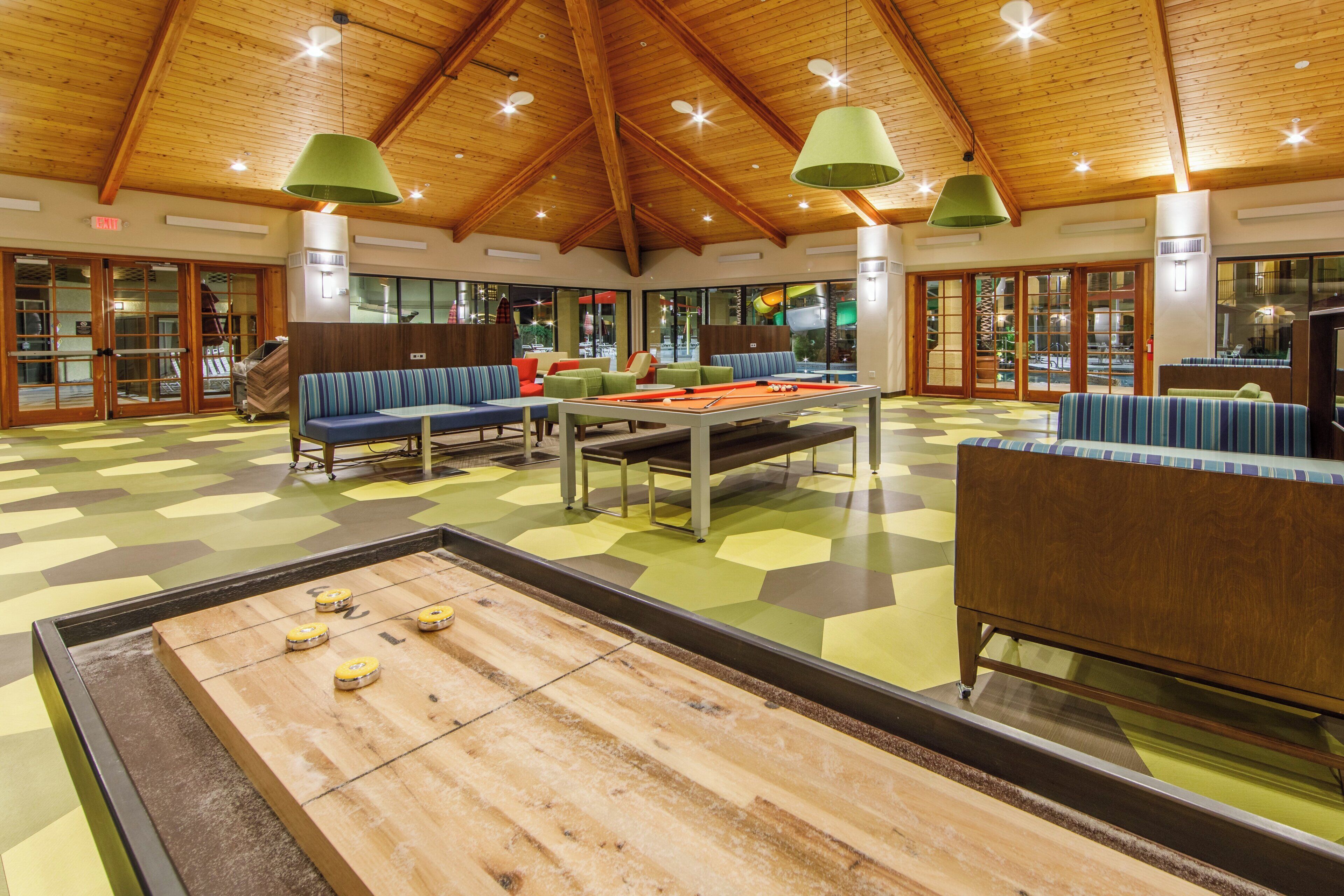 A spacious indoor area with a pool table, seating arrangements, and a high wooden ceiling.