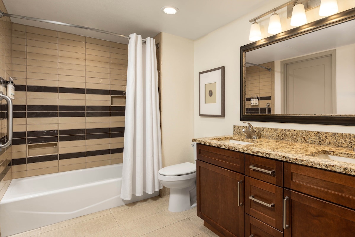 Une salle de bain comprenant une baignoire, des toilettes, un meuble-lavabo avec un évier et un grand miroir.