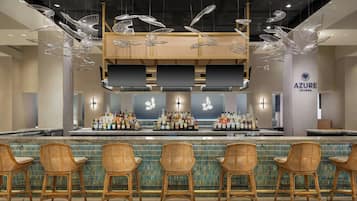 A bar area with wicker chairs, a bar counter with bottles, and a sign for Azure Lounge.
