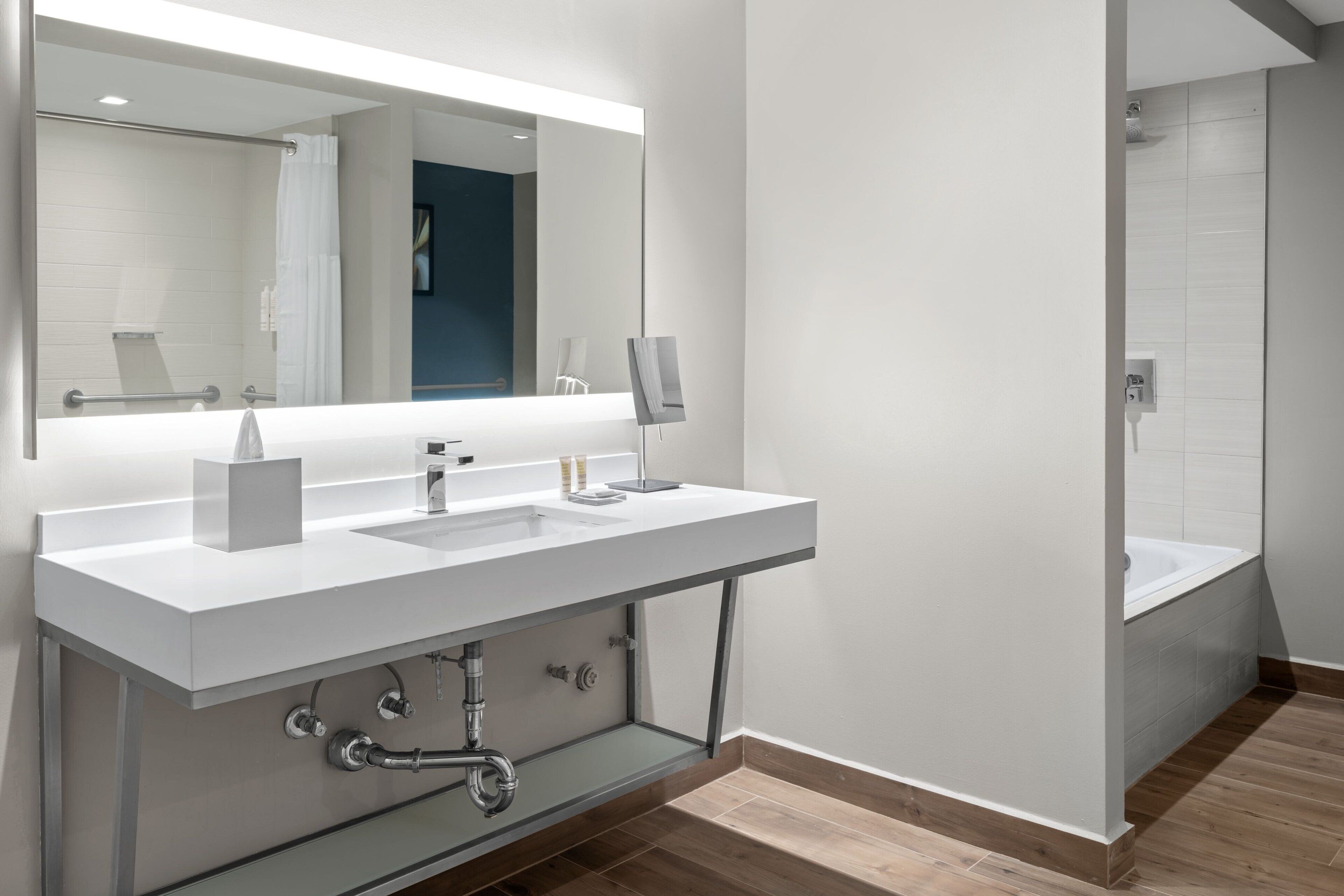 Une salle de bain moderne avec un grand miroir, deux lavabos et une douche.