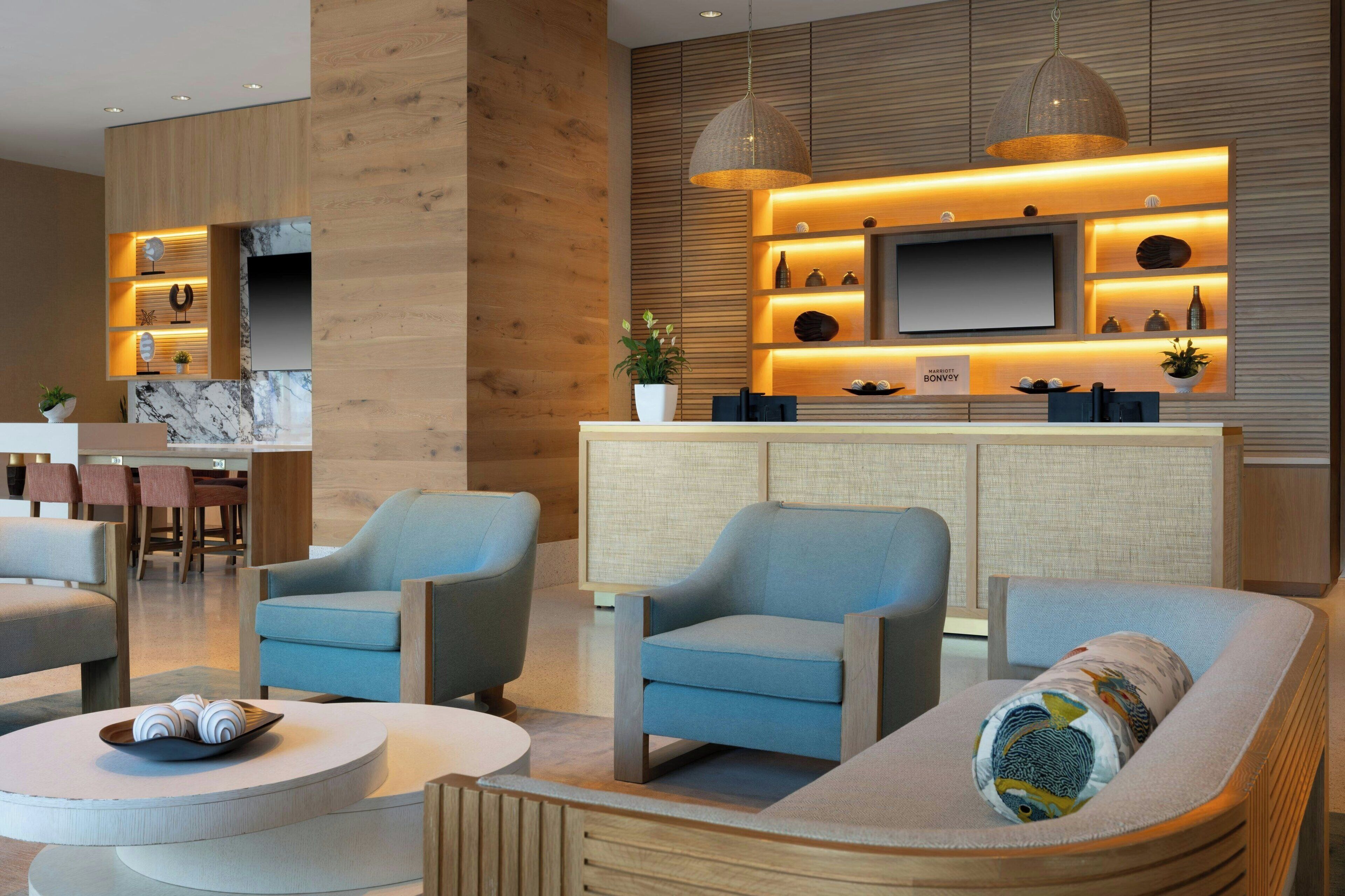 A modern living room with a TV, seating, and a kitchen area in the background.