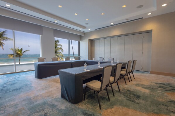 Un salón de conferencias con una larga mesa, sillas y vistas al océano.