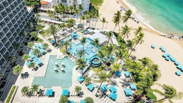 Een resort met een groot zwembad, meerdere lounges en een strand met parasols.