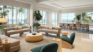 A spacious living area with a large window overlooking the ocean, featuring a sofa, chairs, and a dining table. - San Juan Marriott Resort and Stellaris Casino (San Juan)