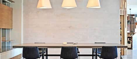 Una cocina moderna con una mesa larga y tres sillas, luces colgantes y una decoración en tonos neutros.