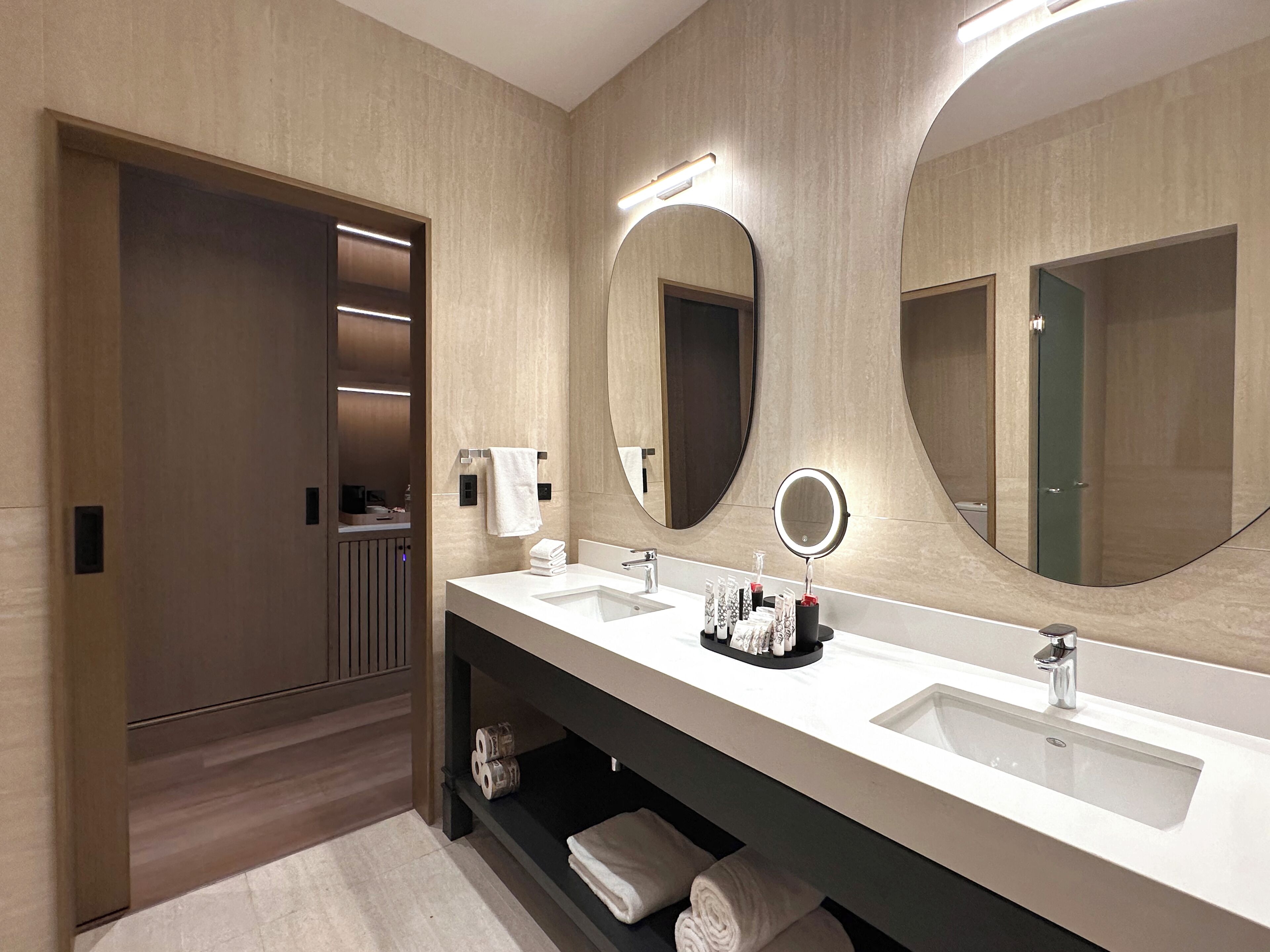 Une salle de bain moderne avec deux lavabos, un grand miroir et un porte-serviettes.