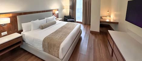 A hotel room with a large bed, bedside tables, a desk, a chair, and a TV.