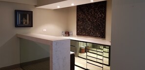 A modern hotel lobby with a marble reception desk, a framed artwork above it, and a decorative wall panel. - Antaris Cintermex (Monterrey)
