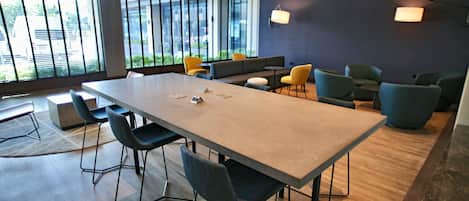 Una sala de conferencias moderna con una gran mesa, sillas y un sofá.