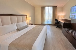 A hotel room with a large bed, a desk, a chair, and a television. - Antaris Cintermex (Monterrey)