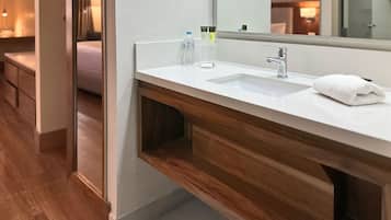 A modern bathroom with a white sink, wooden vanity, and a large mirror.