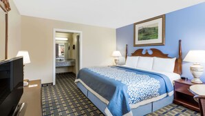 Ein Hotelzimmer mit Bett, Fernseher, Schreibtisch und einem durchgegangenen Tür sichtbaren Badezimmer.