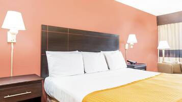 Une chambre d’hôtel avec un lit, des tables de chevet, des lampes et une chaise.