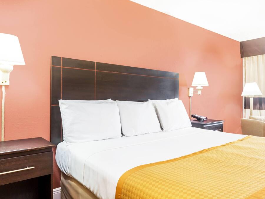 Une chambre d’hôtel avec un lit, des tables de chevet, des lampes et une chaise.