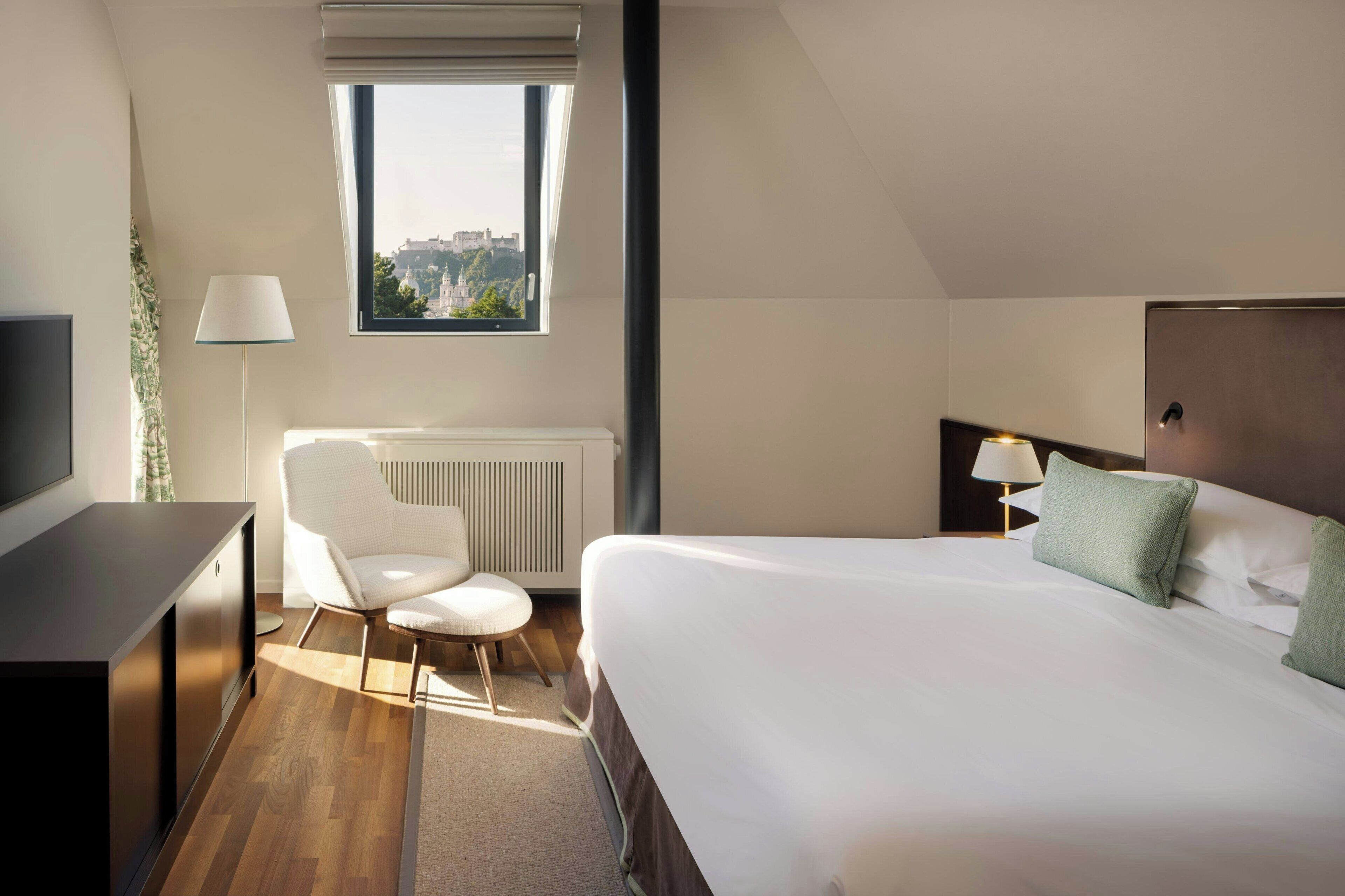 Habitación de hotel con una cama grande, un escritorio, una silla, una ventana con vistas y un radiador.