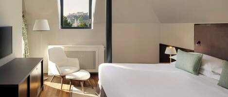 Habitación de hotel con una cama grande, un escritorio, una silla, una ventana con vistas y un radiador.