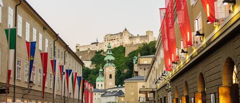A crowded street with historic buildings and a castle in the background.