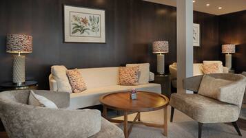 A modern living room with a white sofa, two armchairs, a round coffee table, and two floor lamps with patterned shades.