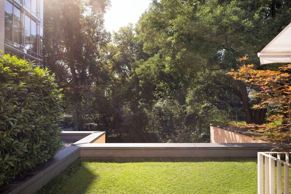 A landscaped garden with a grassy area, a wooden bench, and a white fence.