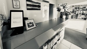 A reception desk with a digital screen displaying the Seasonal South Motel & Function Centre logo, a framed picture, and a wall-mounted clock. - Seasonal South Motel & Function Centre (Ulverstone)