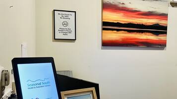 A desk with a computer monitor displaying the Seasonal South Motel & Function Centre website, a framed picture of a beach scene, and a no-smoking sign on the wall.