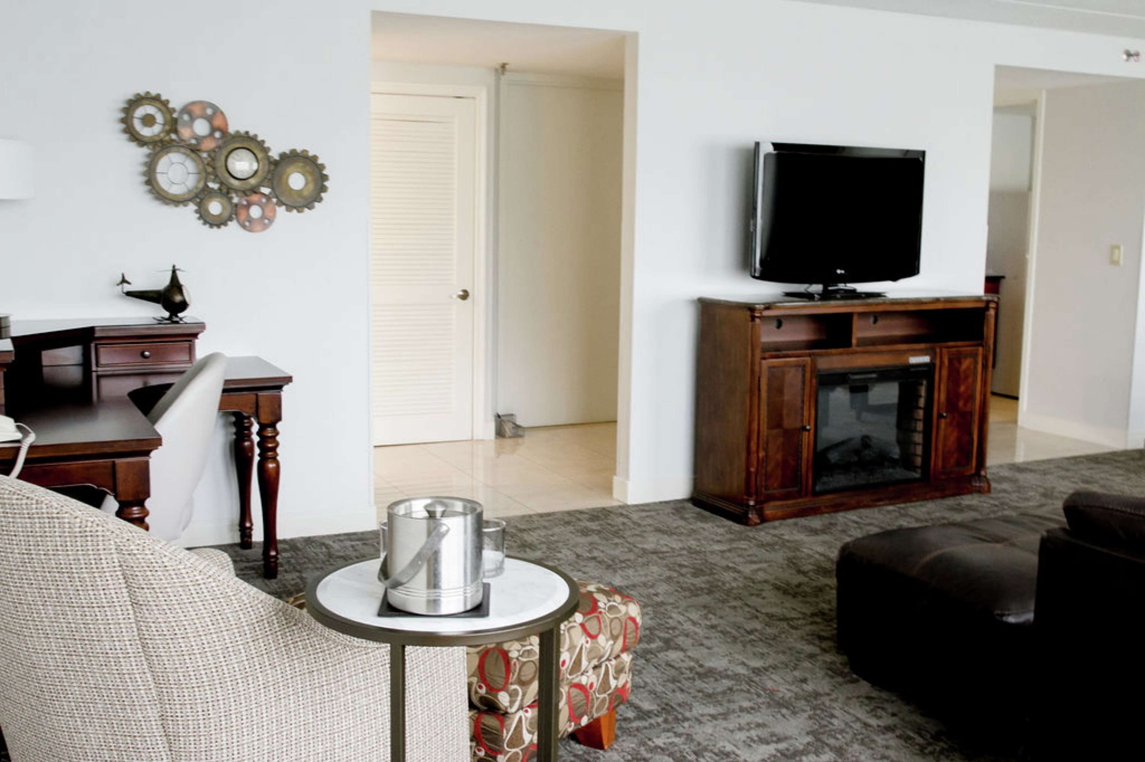 Un salon comprenant un téléviseur, un meuble, une table basse et une porte donnant sur une autre pièce.