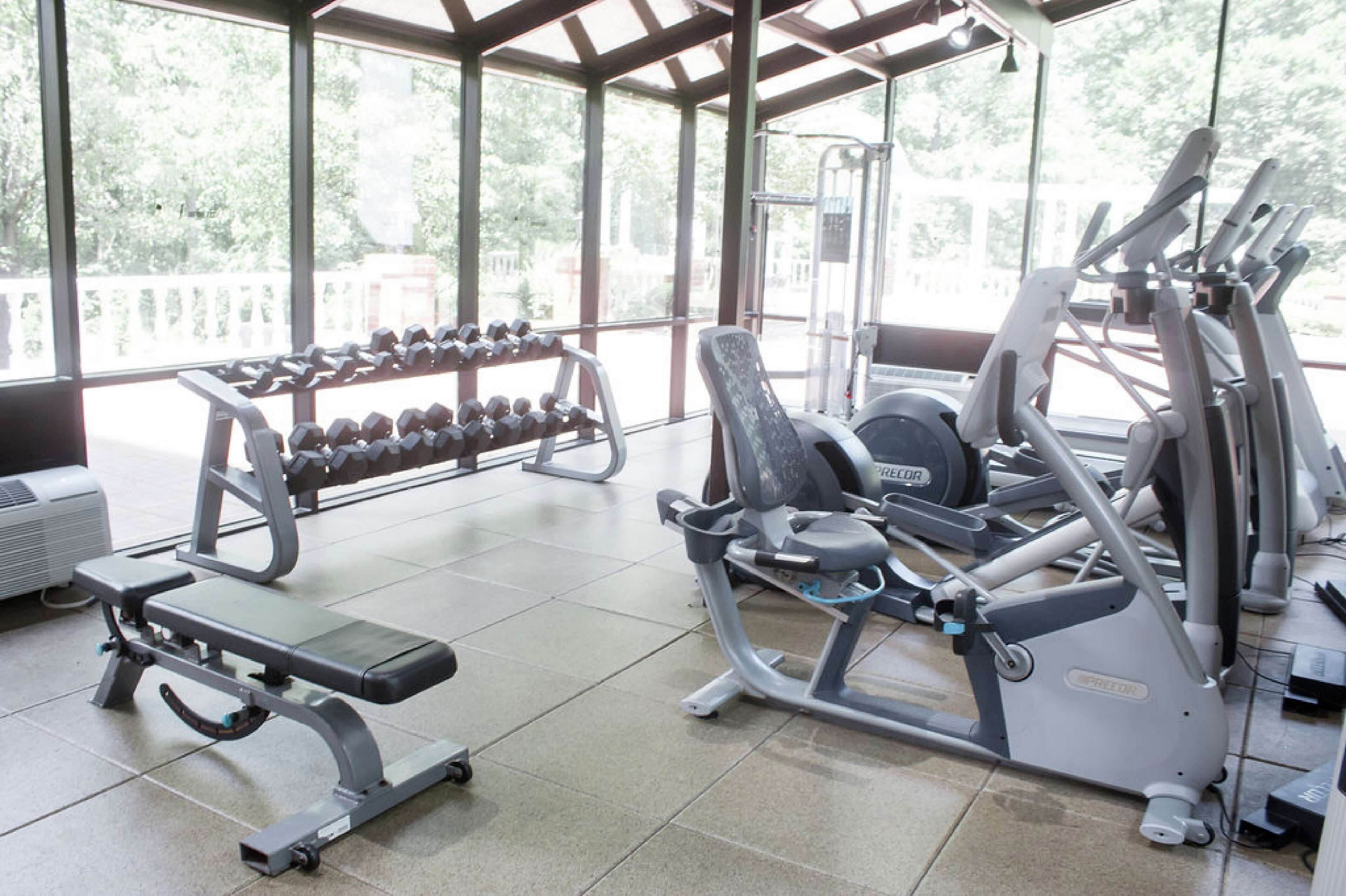 A gym with various exercise equipment, including dumbbells, a bench, and cardio machines.
