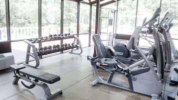 A gym with various exercise equipment, including dumbbells, a bench, and cardio machines.