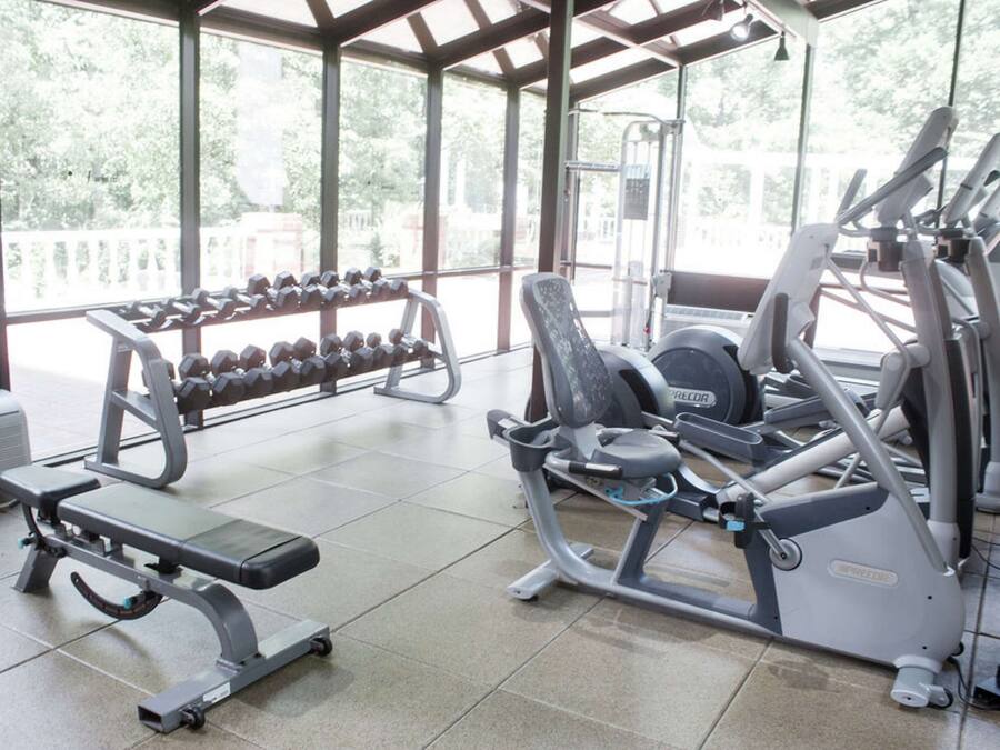 A gym with various exercise equipment, including dumbbells, a bench, and cardio machines.