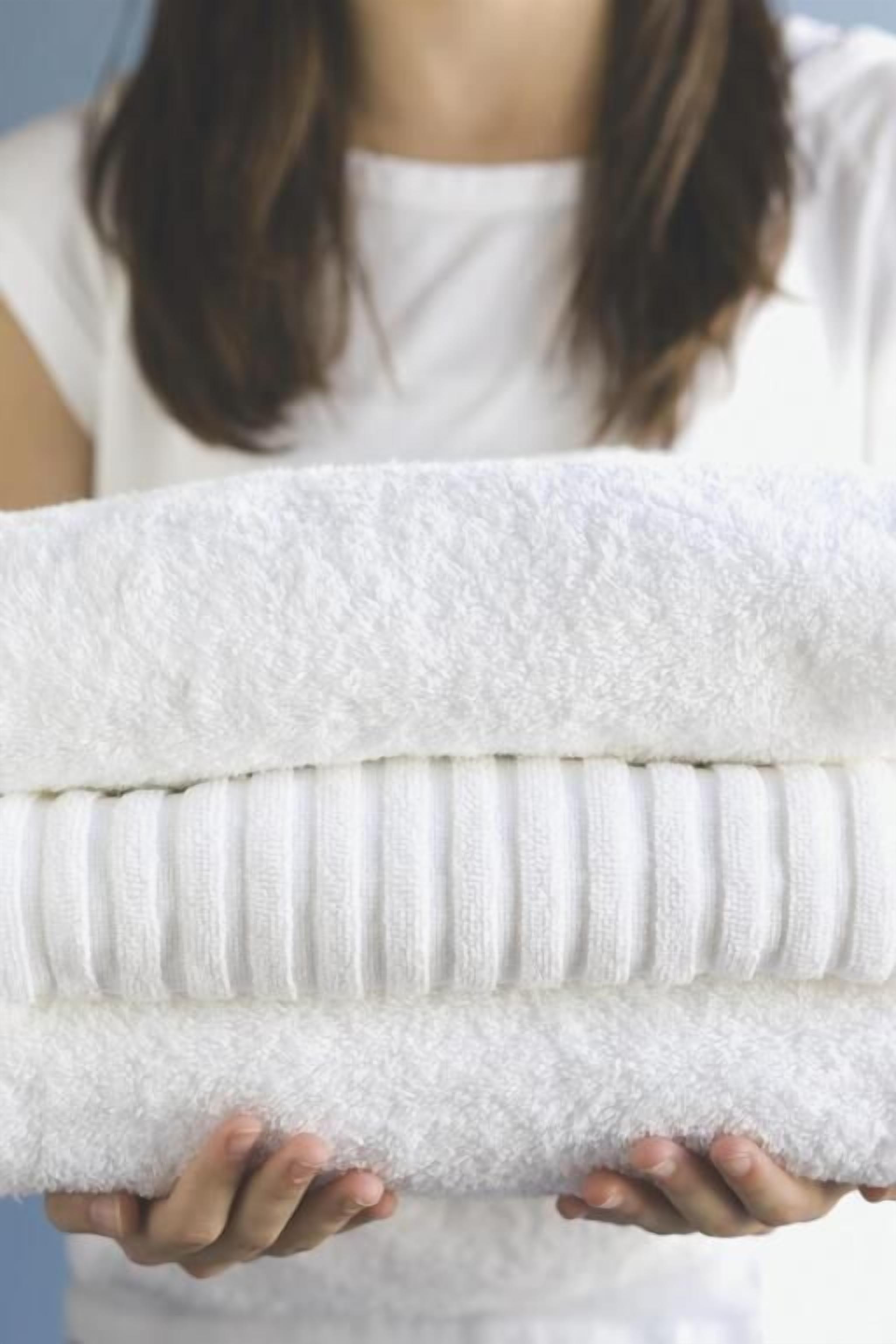 A person holding a folded white towel.