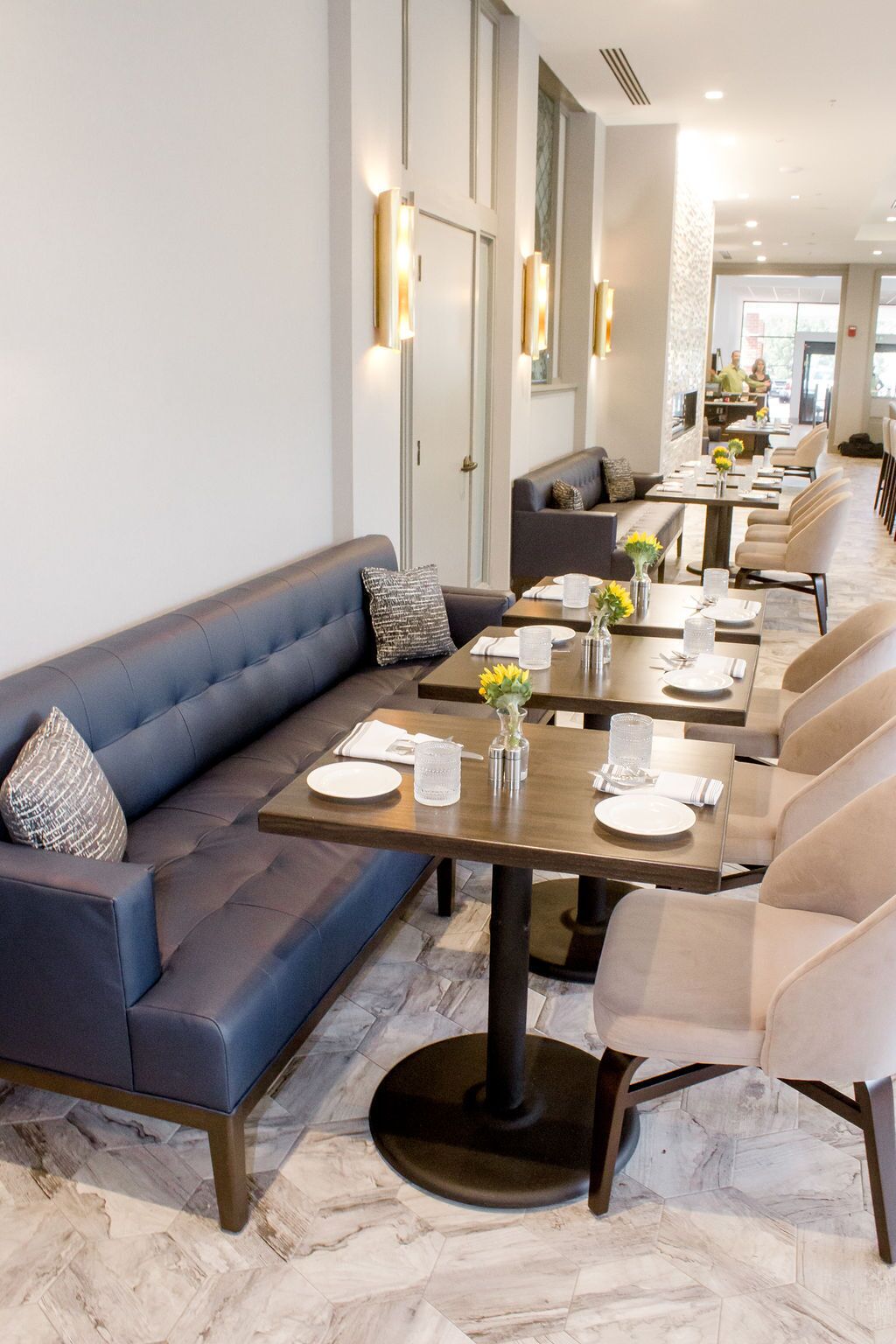 A modern dining area with a long table, cushioned seating, and decorative vases.