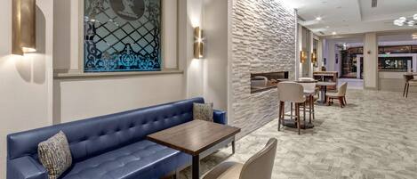 A modern lounge area with a blue sofa, a wooden table, and chairs.