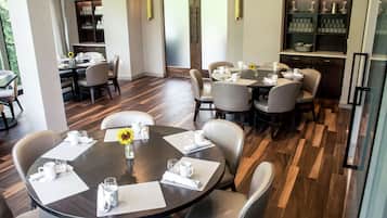A dining area with round tables, chairs, and a central vase.