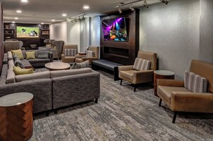 Una sala de estar moderna con un televisor de pantalla plana grande, asientos cómodos y una estantería decorativa.