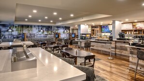 Un ristorante moderno con tavoli in marmo, sedie a fantasia, un'area bar e un murale sulla parete.