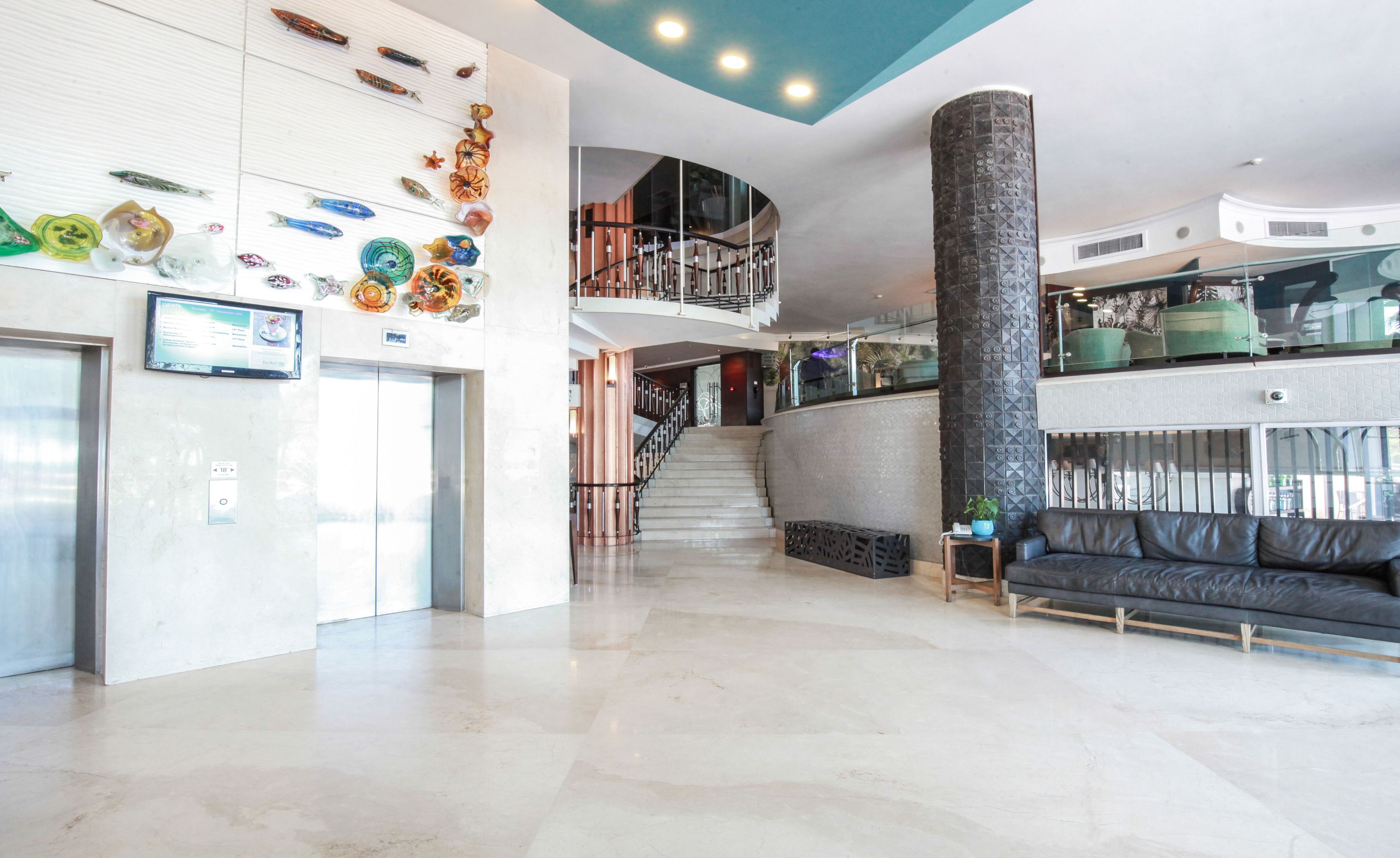 A spacious lobby with a curved staircase, a reception desk, and a modern seating area.